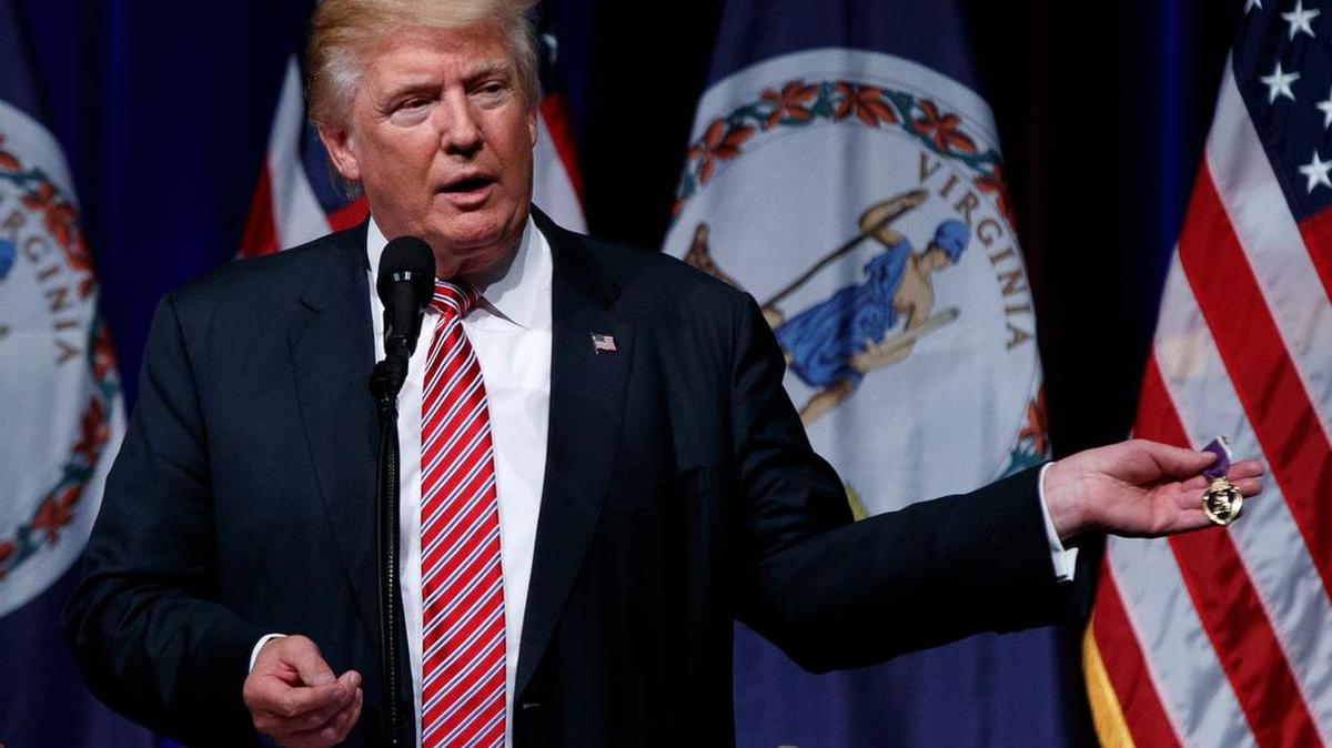 Republican presidential candidate Donald Trump holds a Purple Heart medal given to him by a supporter during a campaign rally at Briar Woods High School, Tuesday, Aug. 2, 2016, in Ashburn, Va.