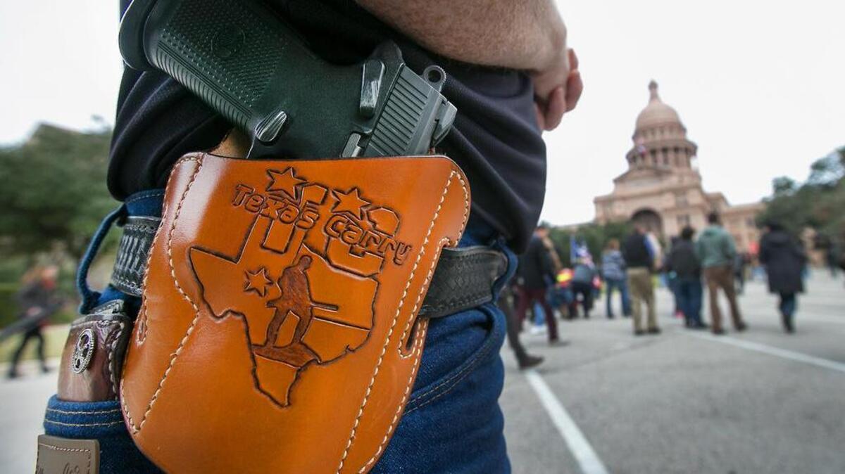 Terry Holcomb, Executive Director of Texas Carry happily displays his customized holster as he walks to the Capitol for a rally earlier this month.