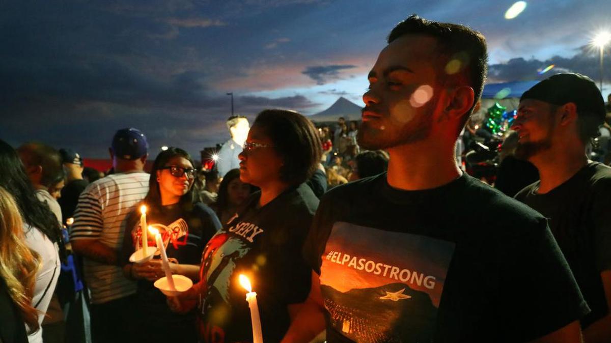 People hold candles during a vigil at the makeshift memorial to the victims of mass shooting in El Paso, Texas, on Aug. 7, 2019.