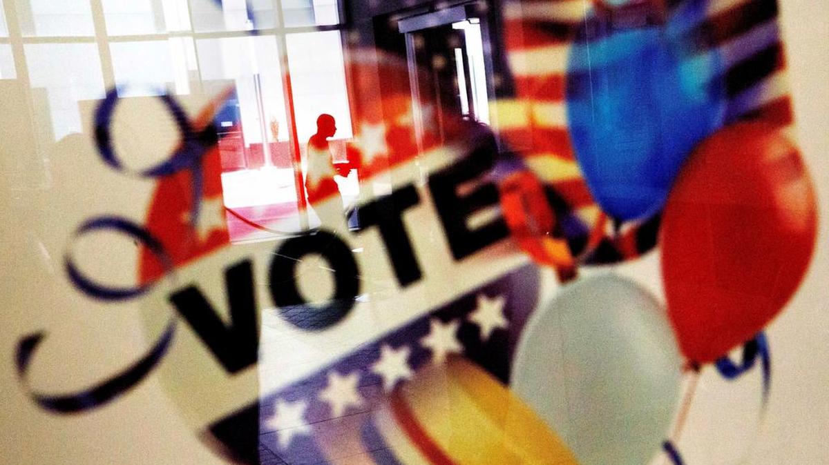 A voter is reflected in the glass frame of a poster in Atlanta during early voting ahead of the Nov. 8 election.