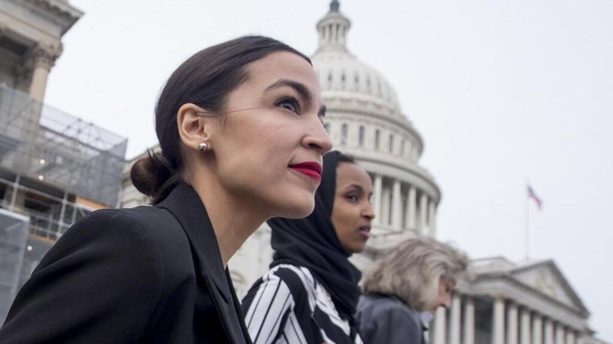 Rep. Alexandria Ocasio-Cortez, left, Rep. Ilhan Omar walk down the House steps to take a group photograph of the House Democratic women members of the 116th Congress on Friday, Jan. 4.