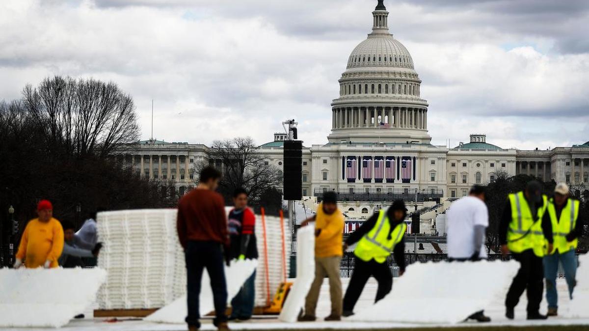 Workers place plastic flooring on the grass of the National Mall in Washington, Wednesday as preparations continue for Friday’s presidential inauguration. (
