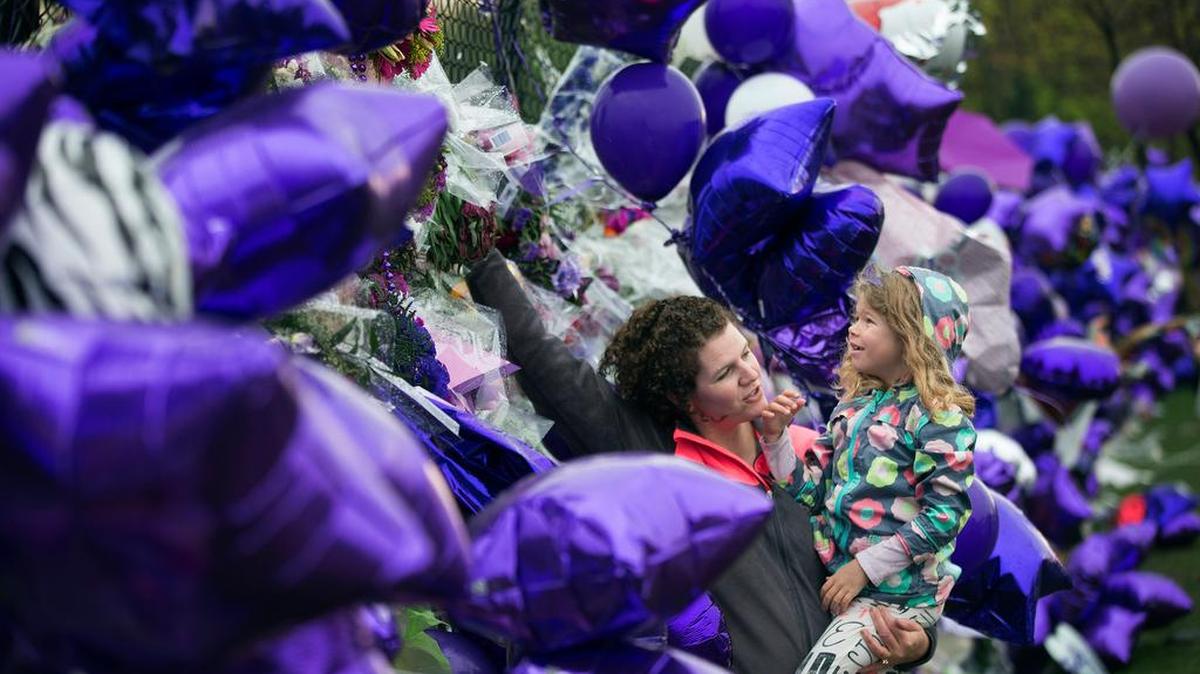 Joy Meuleners holds her niece Keira Abeln at a memorial for Prince at Paisley Park on Sunday, April 24, 2016, in Chanhassen, Minn. When the music superstar died at age 57, it was in the same suburban Minneapolis studio compound where he had lived for years. He could have opted for the glamour of either coast but stayed home, where fans occasionally saw him in local nightclubs, a record store, or just bicycling near Paisley Park. )