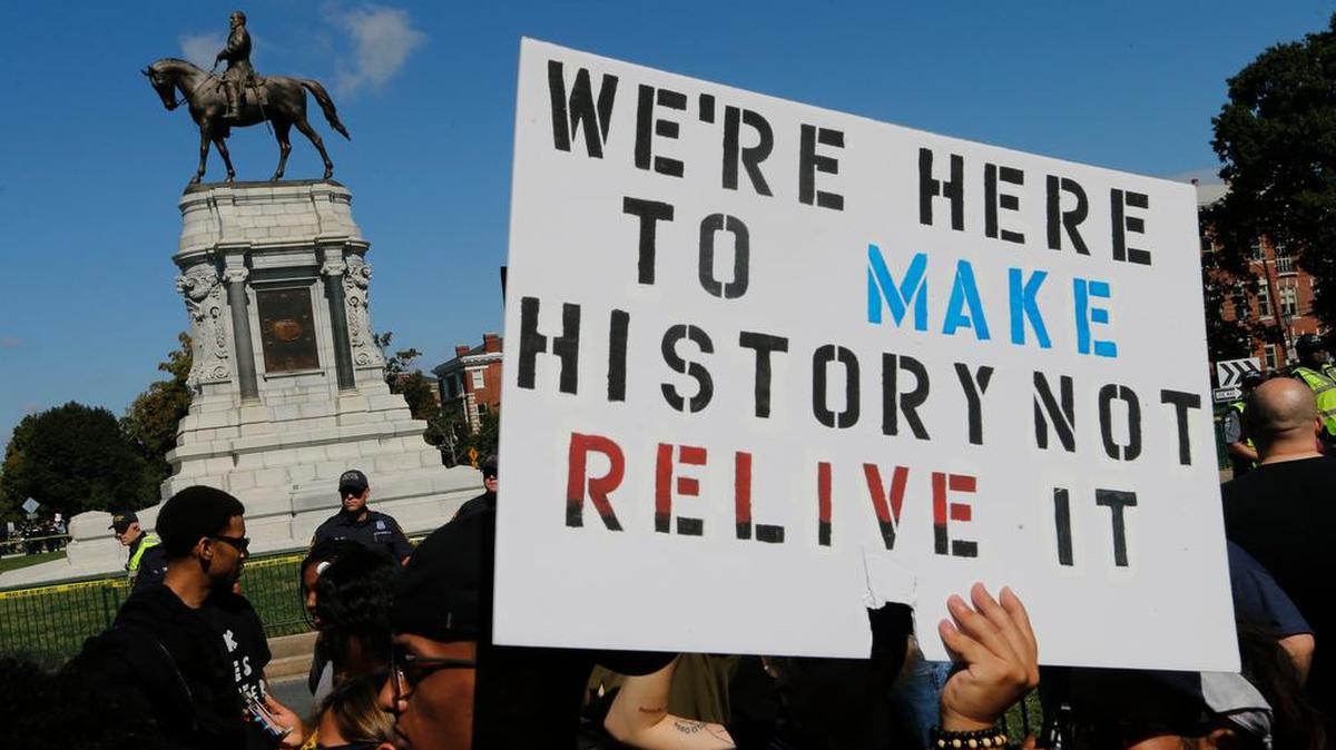 Protesters hold signs in front of the statue of Confederate General Robert E. Lee on Monument Avenue in Richmond, Va., Saturday, Sept. 16, 2017. The group of Confederate demonstrators were escorted out by police after a 50 minute protest.