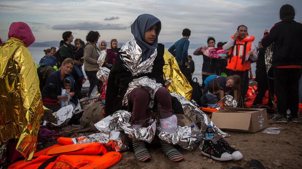 Refugees are helped by volunteers Tuesday after crossing the Aegean sea on a dinghy to the Greek island of Lesbos.