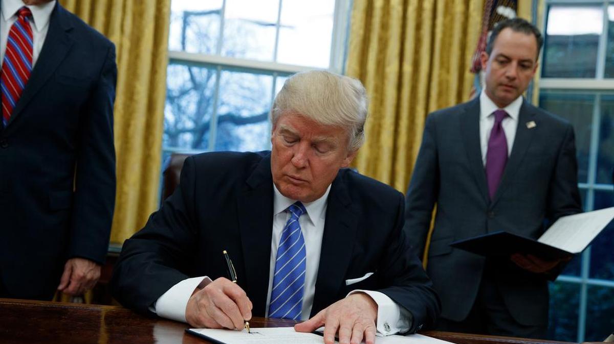 President Donald Trump signs an executive order Monday to withdraw the U.S. from the 12-nation Trans-Pacific Partnership trade pact agreed to under the Obama administration.