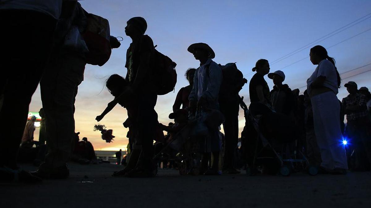A girl plays with a doll as Central American migrants wait in lines for buses donated to transport families with small children on to the next stop, in Niltepec, Oaxaca state, Mexico on Oct. 30.