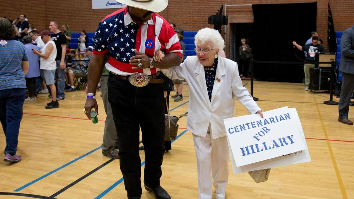 John Goodie escorts Democratic presidential candidate Hillary Clinton supporter 101-year-old Jerry Emmett of Prescott, Ariz., to her seat before Clinton arrives to speak at a campaign event at Carl Hayden Community High School in Phoenix, Monday, March 21, 2016.