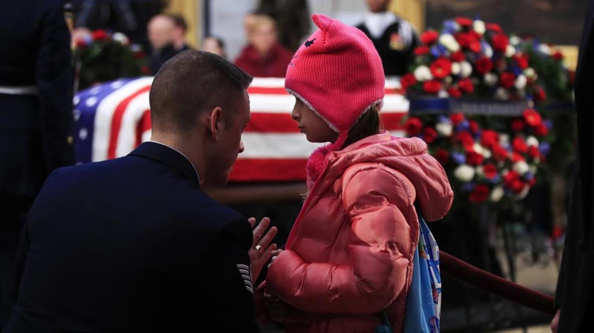 Air Force TSgt. Mason Wilmore and his daughter Nevaeh Wilmore, 8, from Fort Meade, Md. pay their last respects to former President George H.W. Bush as he lay in state at the U.S. Capitol.
