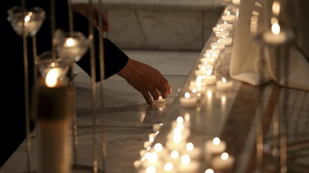 People place candles at the foot of the cross as a sign of unity to those who have been abused during the Mass of Atonement at Cathedral of the Sacred Heart, Friday Sept. 14, 2018 in Richmond, Va.. A Catholic bishop in Virginia is celebrating a “Mass of Atonement” in light of a Pennsylvania grand jury’s allegations that some 300 priests abused more than 1,000 children over 70 years and bishops covered up for them. (Shelby Lum/Richmond Times-Dispatch via AP)