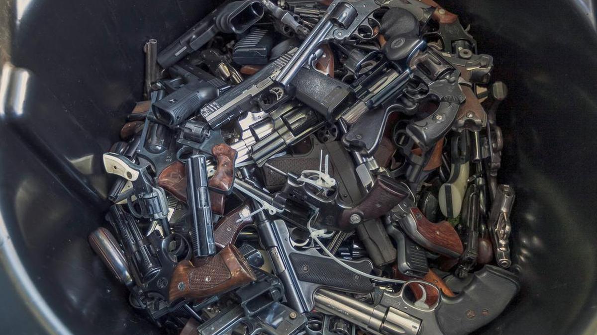 Handguns fill up a trash can for recycling at the LA Memorial Sports Arena in Los Angeles.