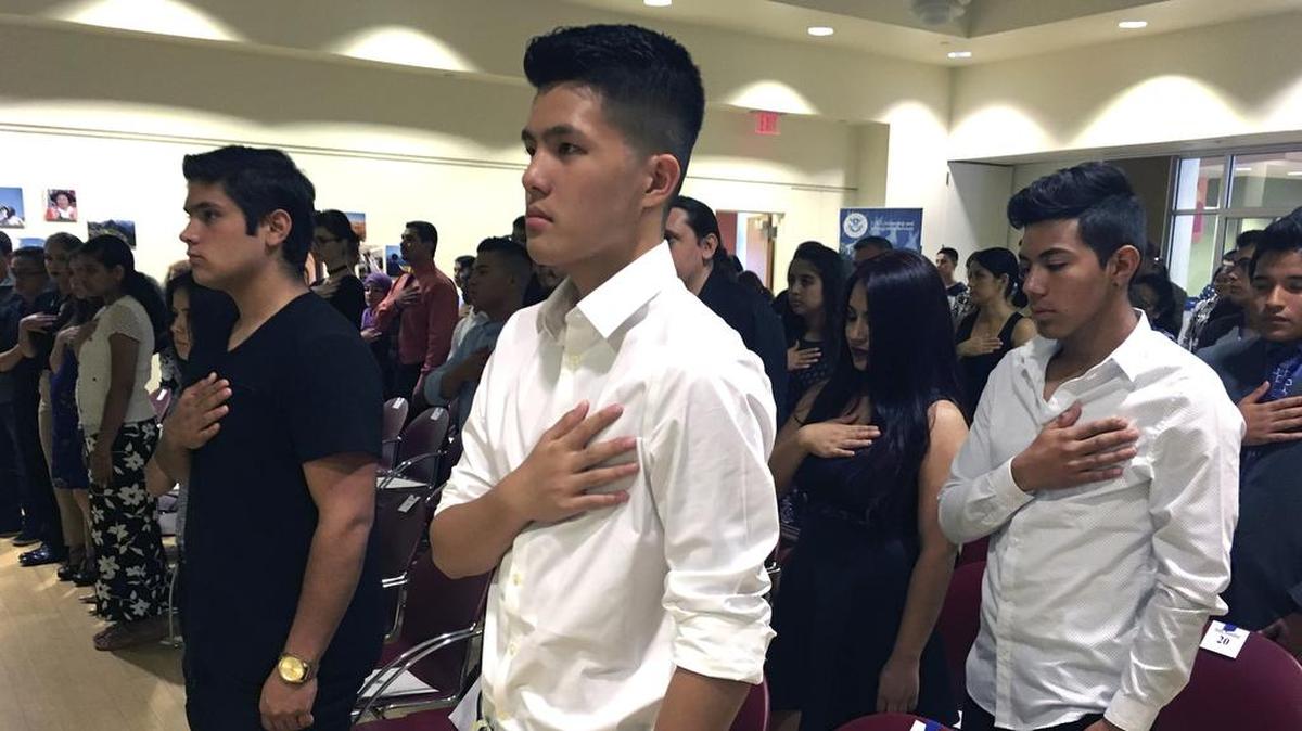 In this Aug. 19, 2016 file photo, Long Chi Vong, 16, center and other immigrants stand for the U.S. Pledge of Allegiance before taking the Oath of Citizenship at a ceremony in Rio Rancho, N.M.