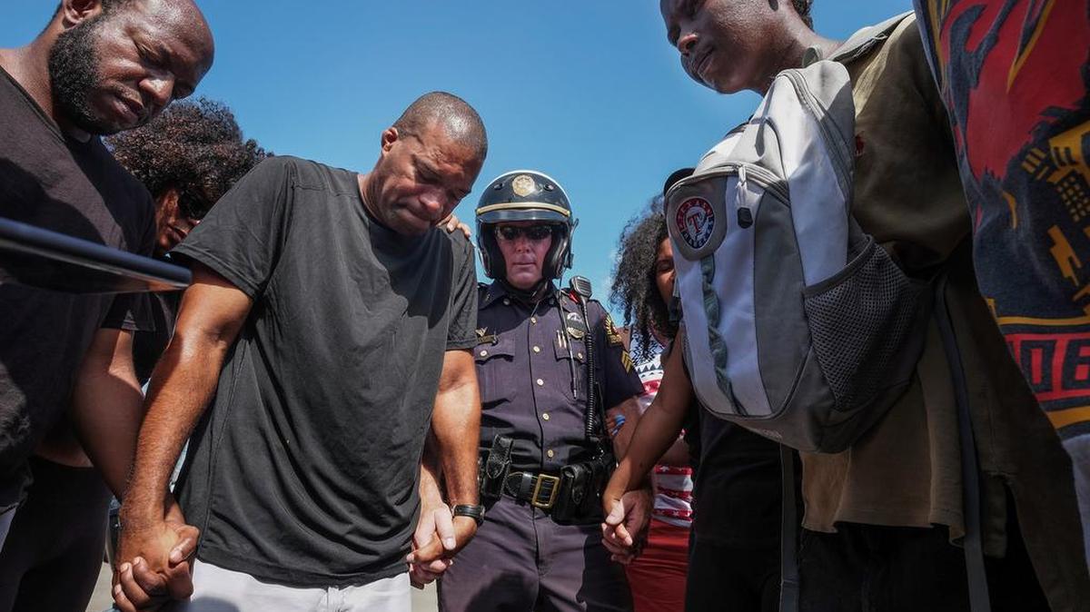 Sgt. Paul Hinton prays with a group of Black Lives Matter marchers in Dallas on Sunday. Hinton said "We are not black or white or hispanic. We are blue."