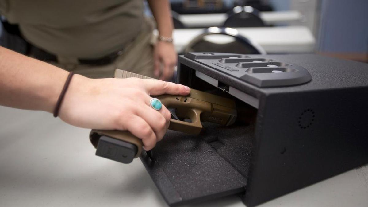 A gun safety instructor shows how to keep a gun in a safe.
