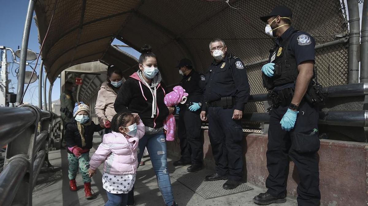 In this Friday, Feb. 26, 2021 file photo, a migrant family wearing face masks crosses the border into El Paso, Texas, in Ciudad Juarez, Mexico.