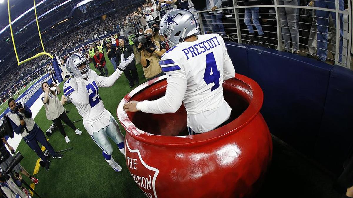 Dallas Cowboys quarterback Dak Prescott (4) celebrates after being lifted into a Salvation Army kettle by running back Ezekiel Elliott (21) after scoring a touchdown against Washington during the second half of an NFL football game in Arlington, Texas, Thursday, Nov. 22, 2018.