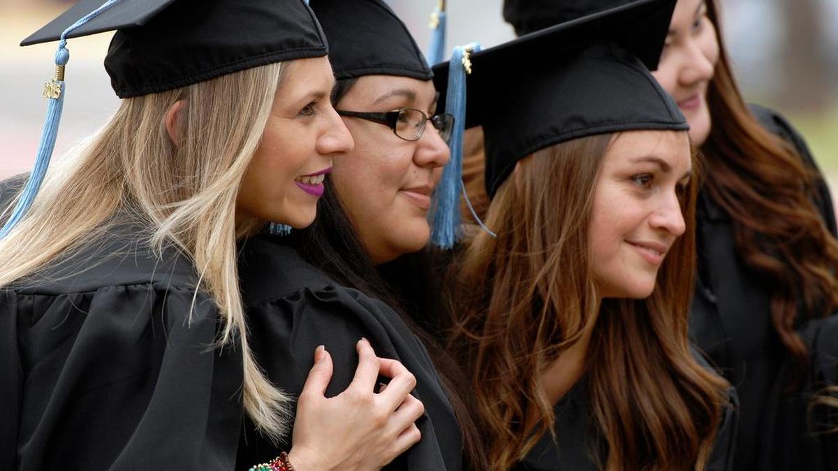 College graduates take photos during fall commencement exercises.
