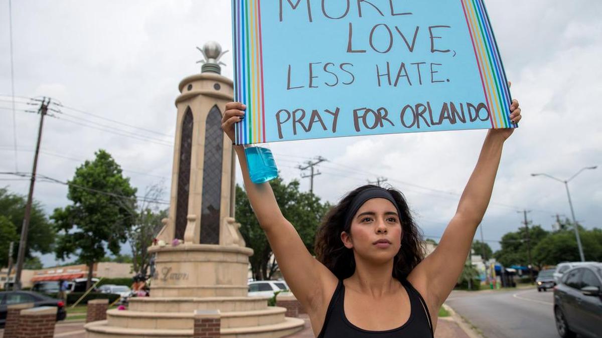 Raquel Flores of Richardson holds up a sign June 12 at the Legacy of Love Monument in Dallas.