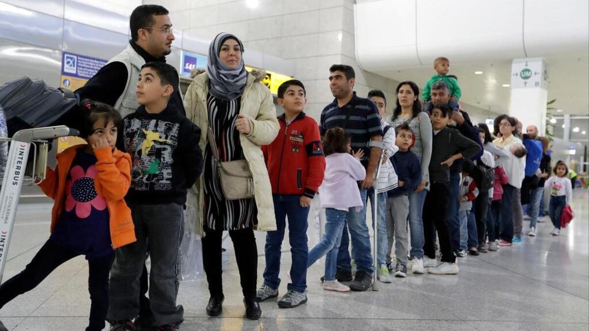 Refugees from Syria and Iraq stand at the Athens airport Monday, waiting to be relocated to Spain.