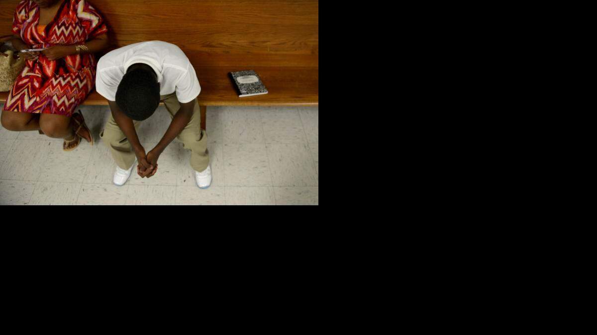 
A boy waits with his mother to speak with a judge at the Henry Wade Juvenile Justice Center in Dallas. 
