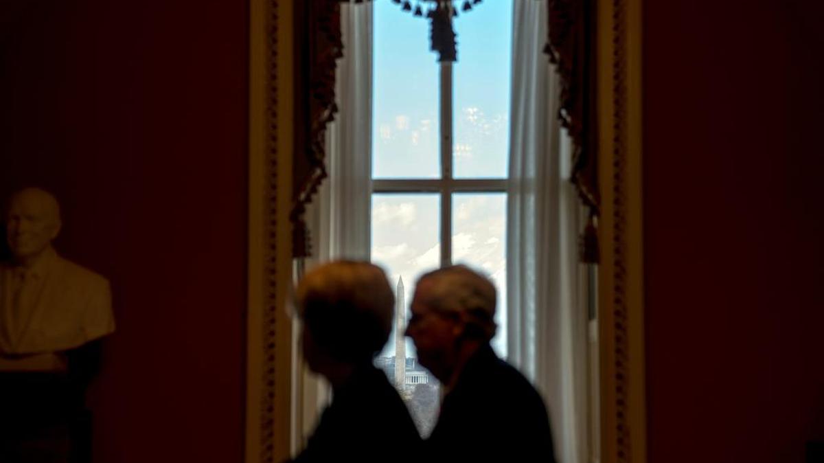 The Washington Monument and the Lincoln Memorial are visible through a window as Senate Majority Leader Mitch McConnell of Ky., right, walks to his office from the Senate floor at the Capitol in Washington, Tuesday, Jan. 23, 2018. The federal government has reopened after a three day shutdown.