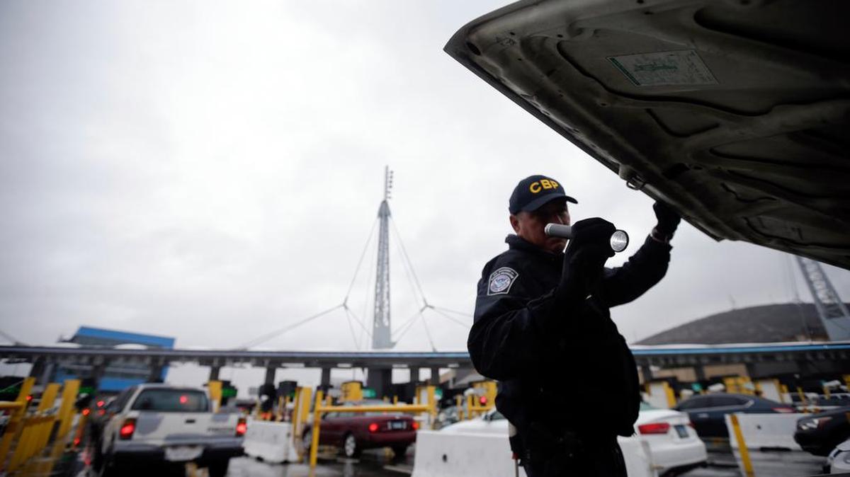 A U.S. Customs and Border Protection (CBP) officer checks under the hood of a car as it waits to enter the U.S. from Tijuana, Mexico through the San Ysidro port of entry in San Diego in 2014. A group of First Amendment attorneys is suing the Trump administration over access to data showing how often citizens and visitors had their electronic devices searched and the contents catalogued at the border.