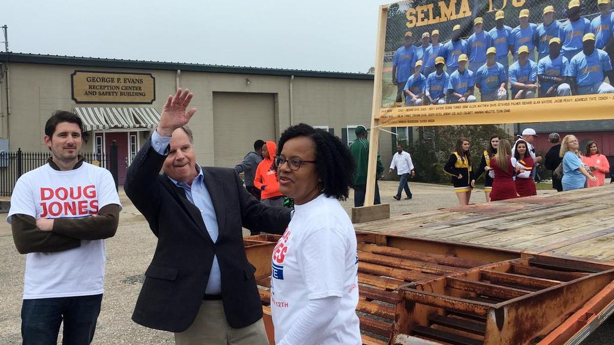 Doug Jones, second form left, the Democratic candidate for U.S. Senate, waves to a supporter as he walks in a Christmas parade, Saturday, Dec, 2, 2017, in Selma, Ala.
