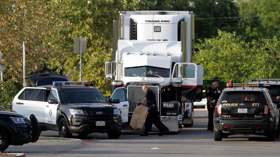 San Antonio police officers investigate the scene where eight people were found dead in a tractor-trailer loaded with at least 30 others outside a Walmart store last month.
