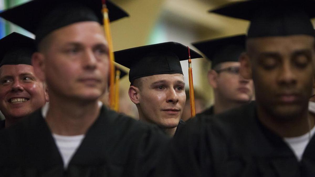 Darrington Unit inmate Leo G. Little, center, listens to his commencement program while wearing a graduation gown. Little and 32 other inmates received a bachelors degree in biblical science last year from the Southwestern Baptist Theological Seminary while serving time in prison.
