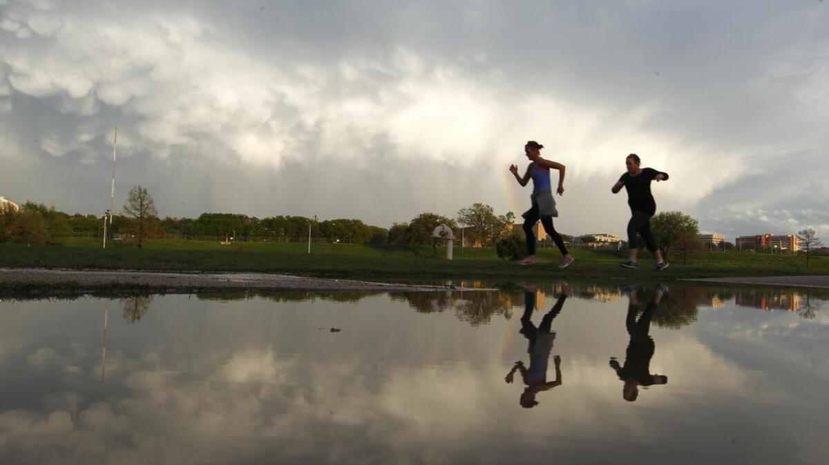 Joggers participating in a social run along the Trinity Trail pass a puddle left by afternoon rains and dramatic skies as storms head east of Tarrant County earlier this year.