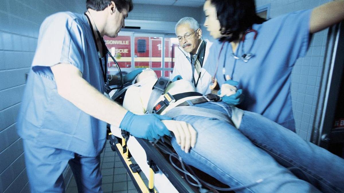 Doctors and nurses assisting patient on gurney.