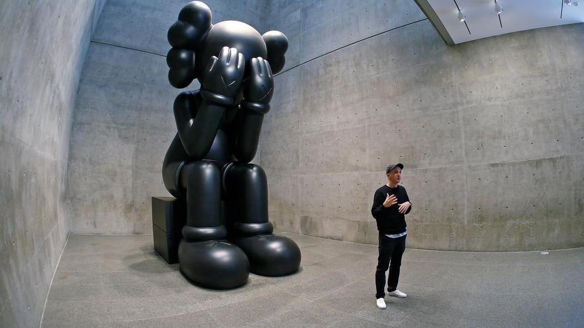 Artist KAWS (Brian Donnelly) is dwarfed by one of his pieces Oct. 19 at a press preview of his “KAWS: Where The End Starts” exhibit at the Modern Art Museum of Fort Worth .