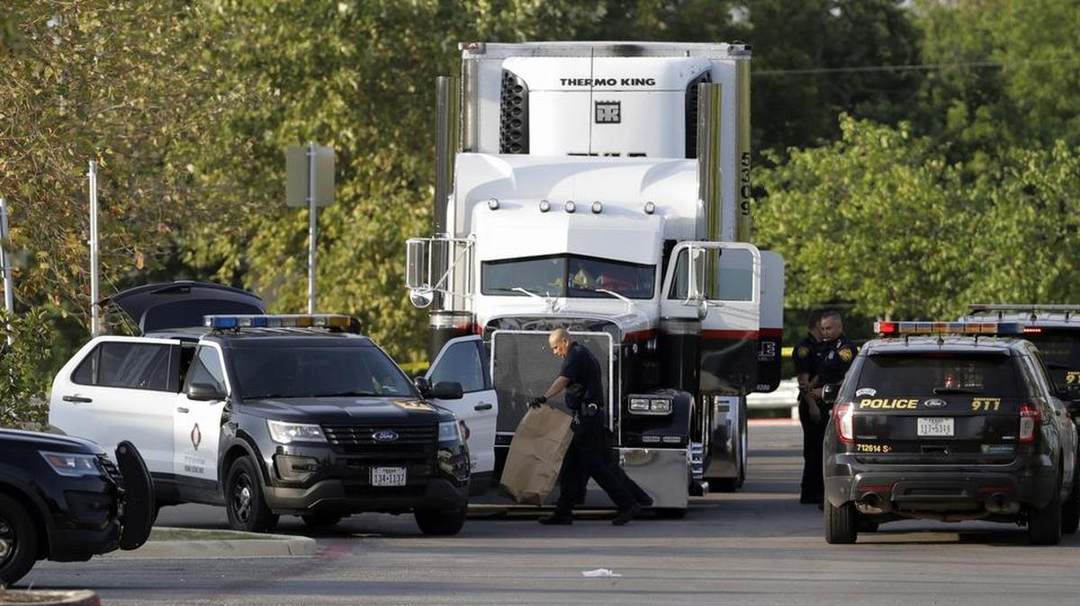 San Antonio police officers investigate the scene where eight people were found dead in a tractor-trailer loaded with at least 30 others outside a Walmart store in stifling summer heat in what police are calling a horrific human trafficking case, Sunday, July 23, 2017, in San Antonio.