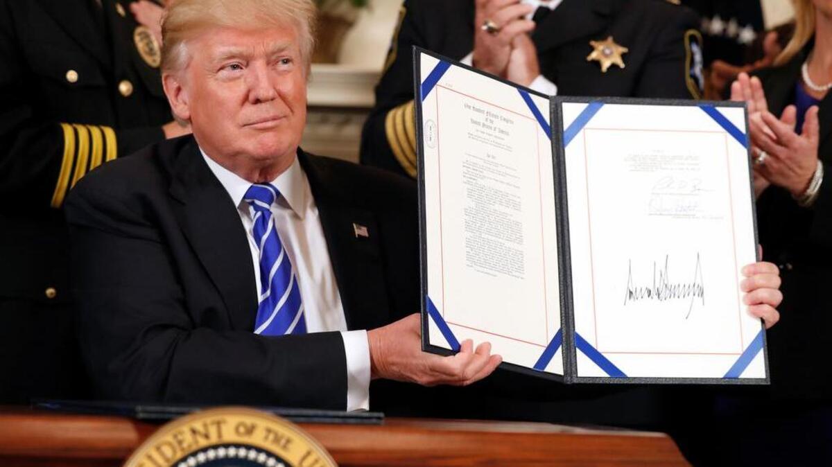 President Donald Trump holds up a signed bill Friday.