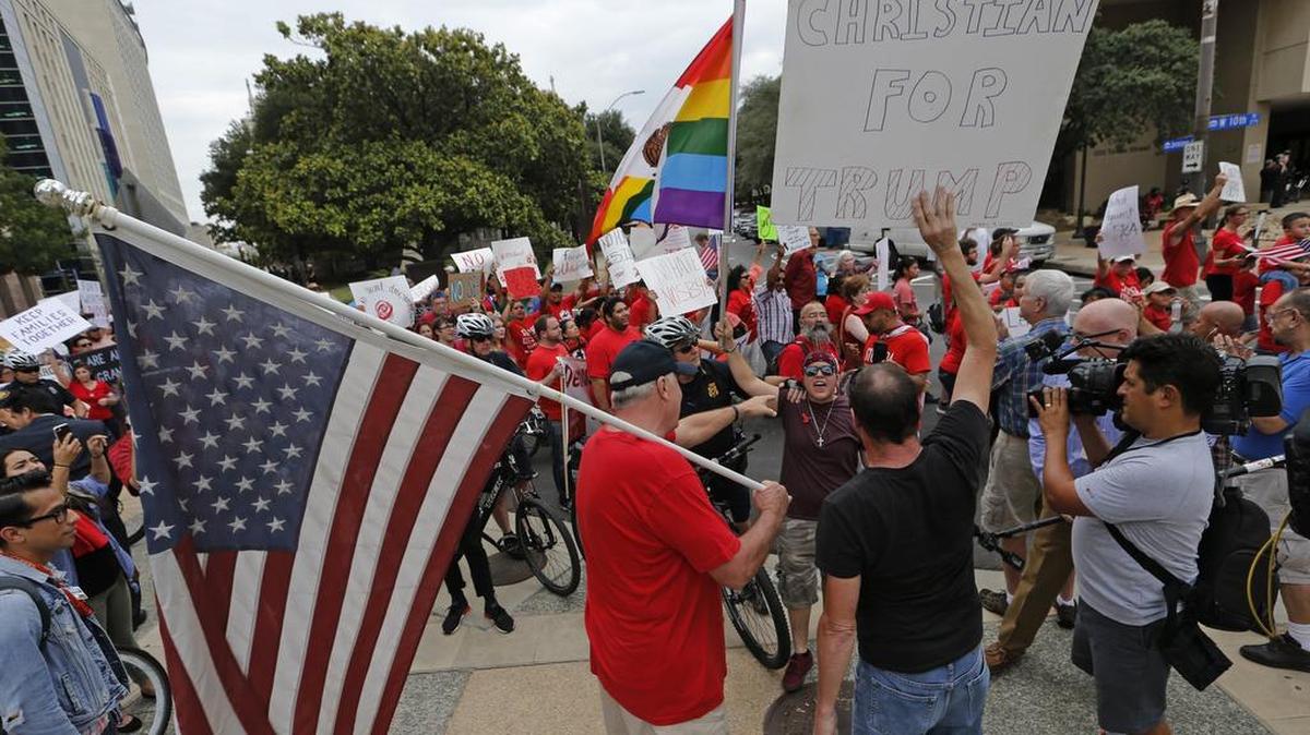 Protesters pass two counter protesters during a "Day of Action" to protest the Texas Senate SB-4 bill against sanctuary cities in downtown Fort Worth, Tuesday, August 1, 2017.