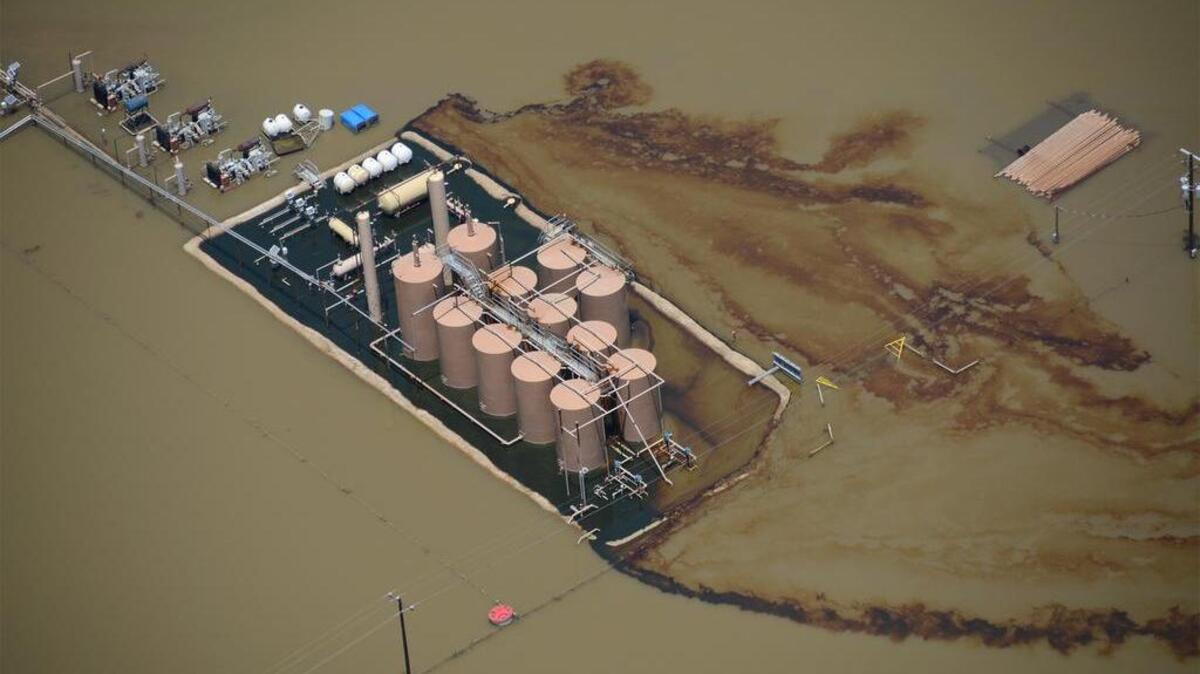 Oil runs from a production site on the lower Trinity River on June 8, 2015, during flooding.