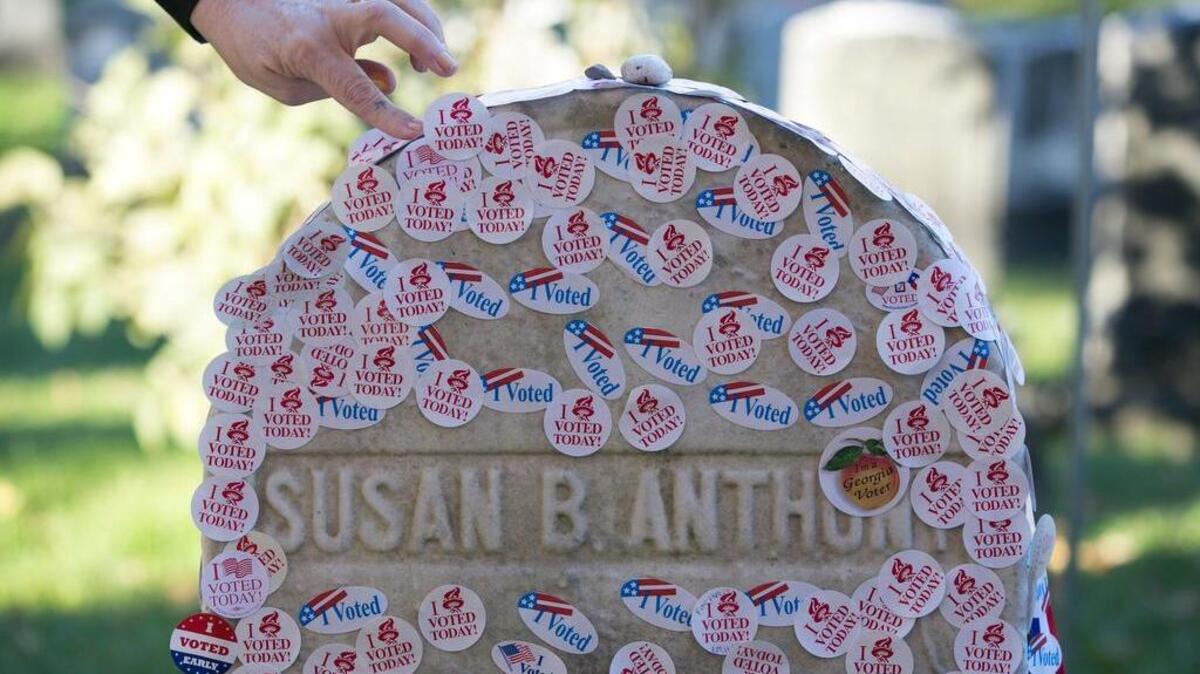 A woman places a voting sticker on the headstone of Susan B. Anthony, a women's suffrage pioneer, on Election Day in Rochester, N.Y., Nov. 8, 2016.