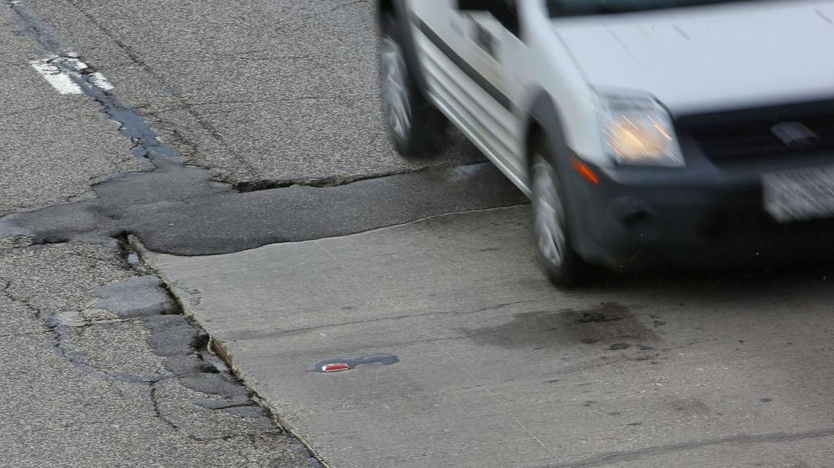 A car encounters a pothole on Interstate 35W. Normal weather cycles make potholes inevitable.