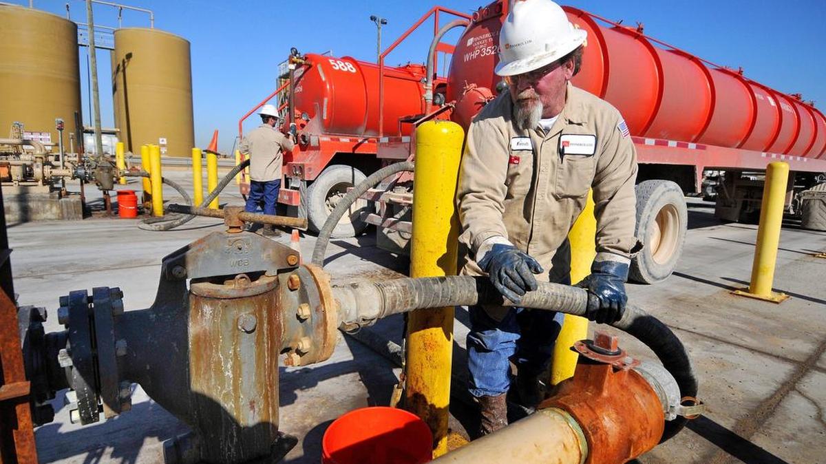Workers unload drilling wastewater at a disposal well for injection deep underground.