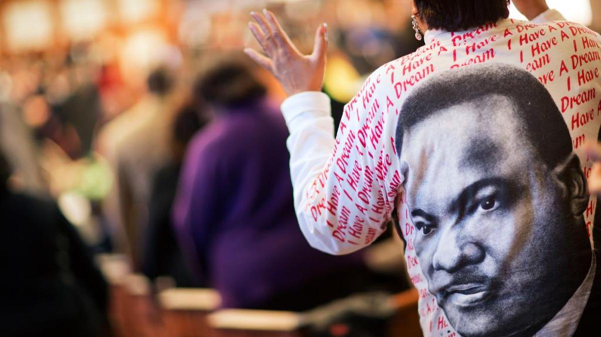 Gail Hollin wears a shirt bearing the image of the Rev. Martin Luther King Jr. as she sings during the Jan. 18 King holiday commemorative service at Ebenezer Baptist Church in Atlanta here he preached.
