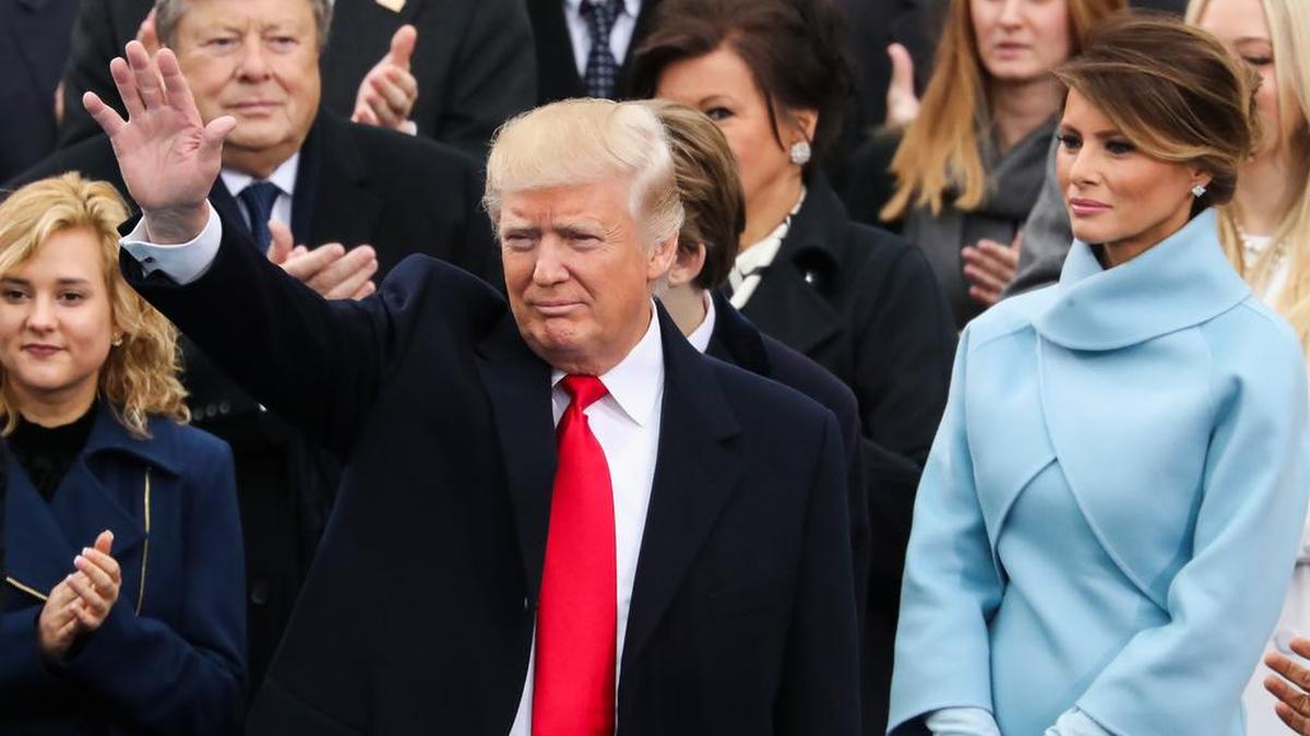 President Donald Trump waves as Melania Trump looks on Friday during his inauguration ceremony.