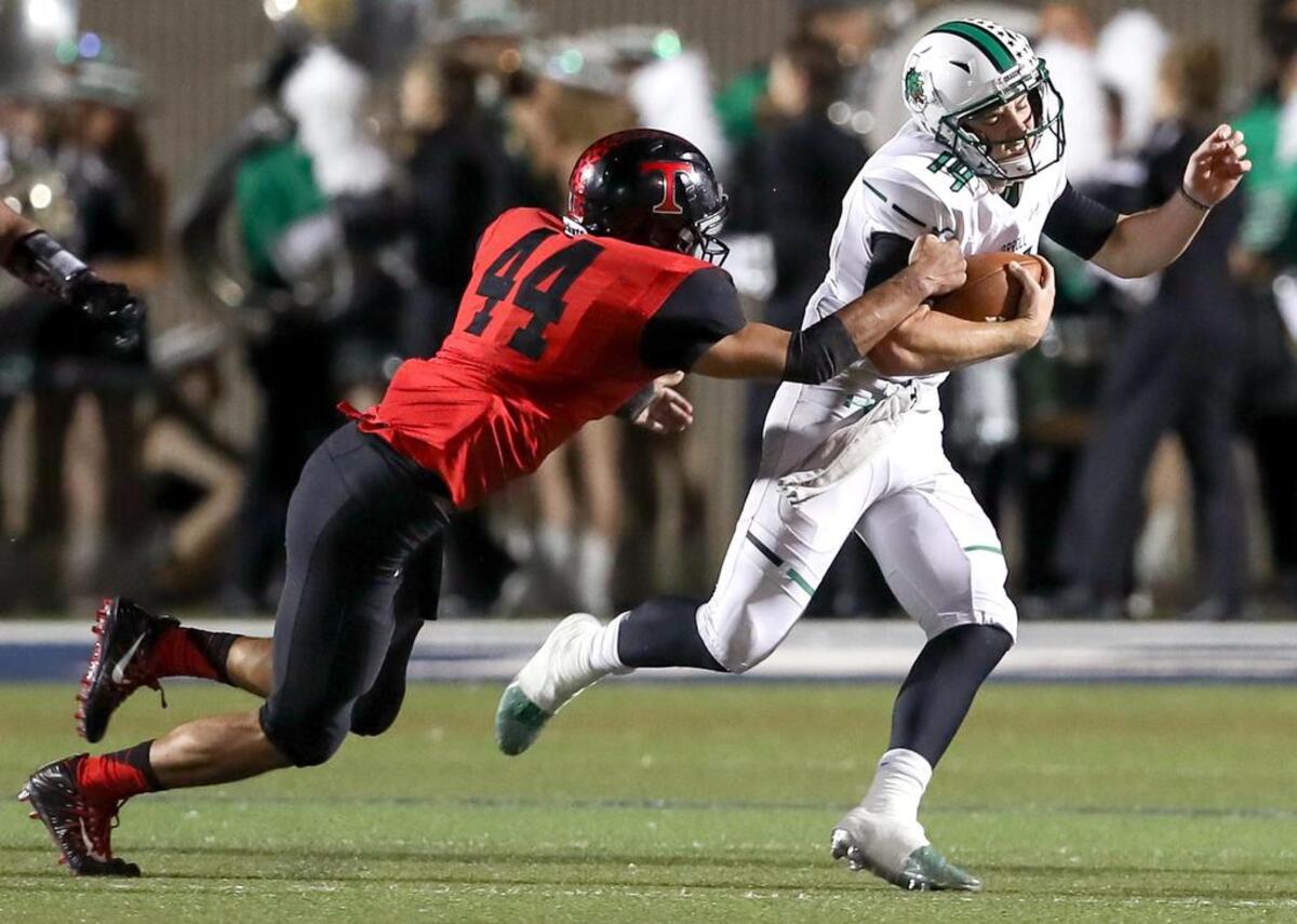 Southlake Carroll quarterback Will Bowers (14) tries to get around Trinity defensive end Isaiah Munoz (44) during the first half, Friday night, October 6, 2017 played at Pennington Field in Bedford.