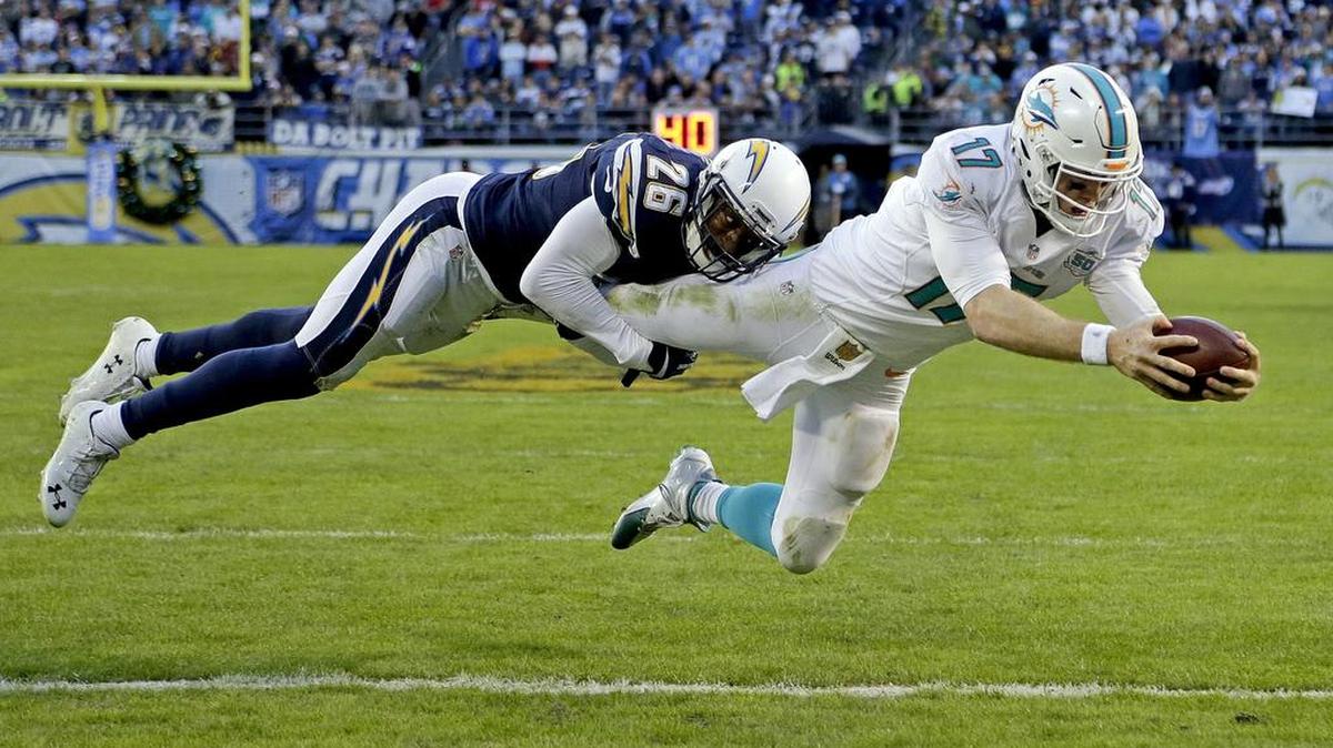Miami Dolphins quarterback Ryan Tannehill, right, scores under pressure by San Diego Chargers cornerback Patrick Robinson Dec. 20, 2015, in San Diego.