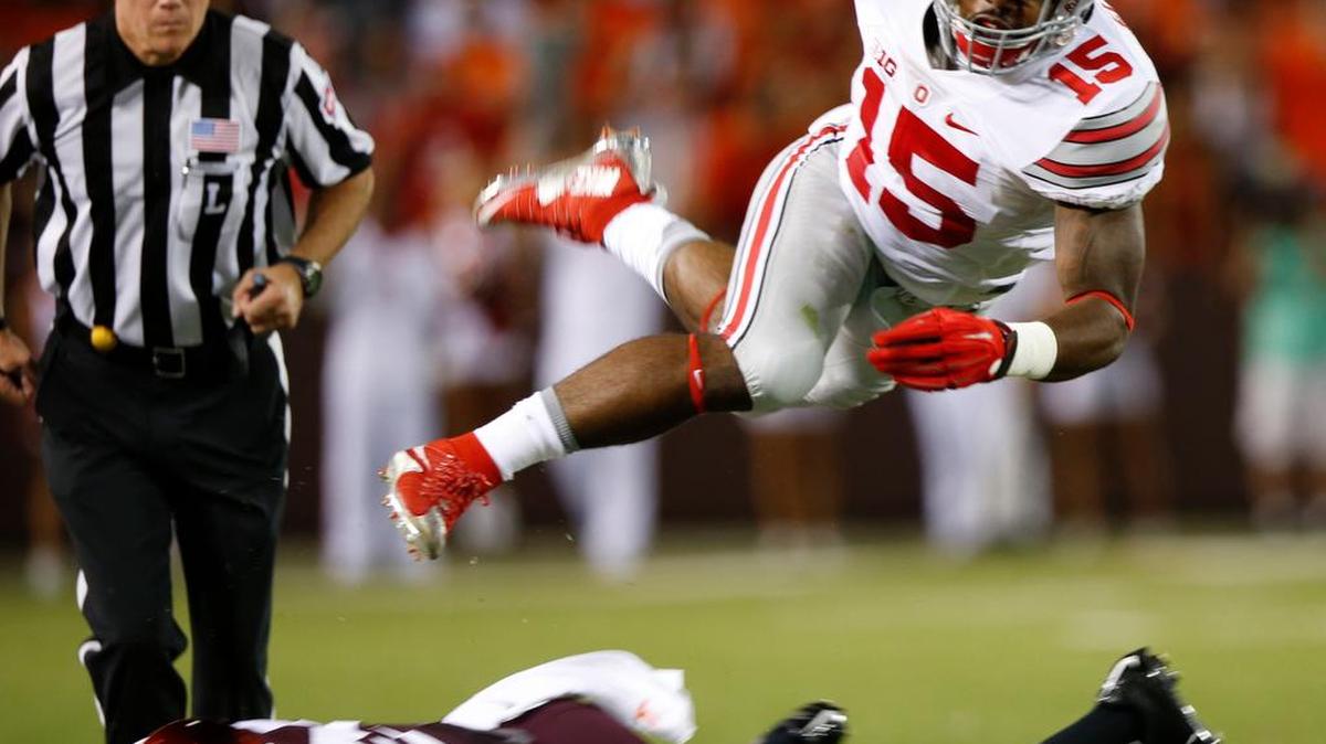 
Ohio State running back Ezekiel Elliott (15) jumps over Virginia Tech safety Desmond Frye (26) during the first half of an NCAA college football game in Blacksburg, Va., Monday, Sept. 7, 2015. 
