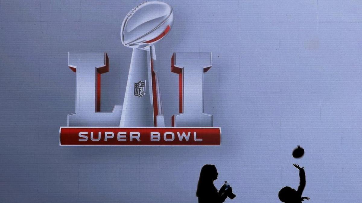 Fans walk past a sign at the NFL Experience ahead of the NFL Super Bowl 51 football game Friday, Feb. 3, 2017, in Houston. The New England Patriots will face the Atlanta Falcons in the Super Bowl Sunday.