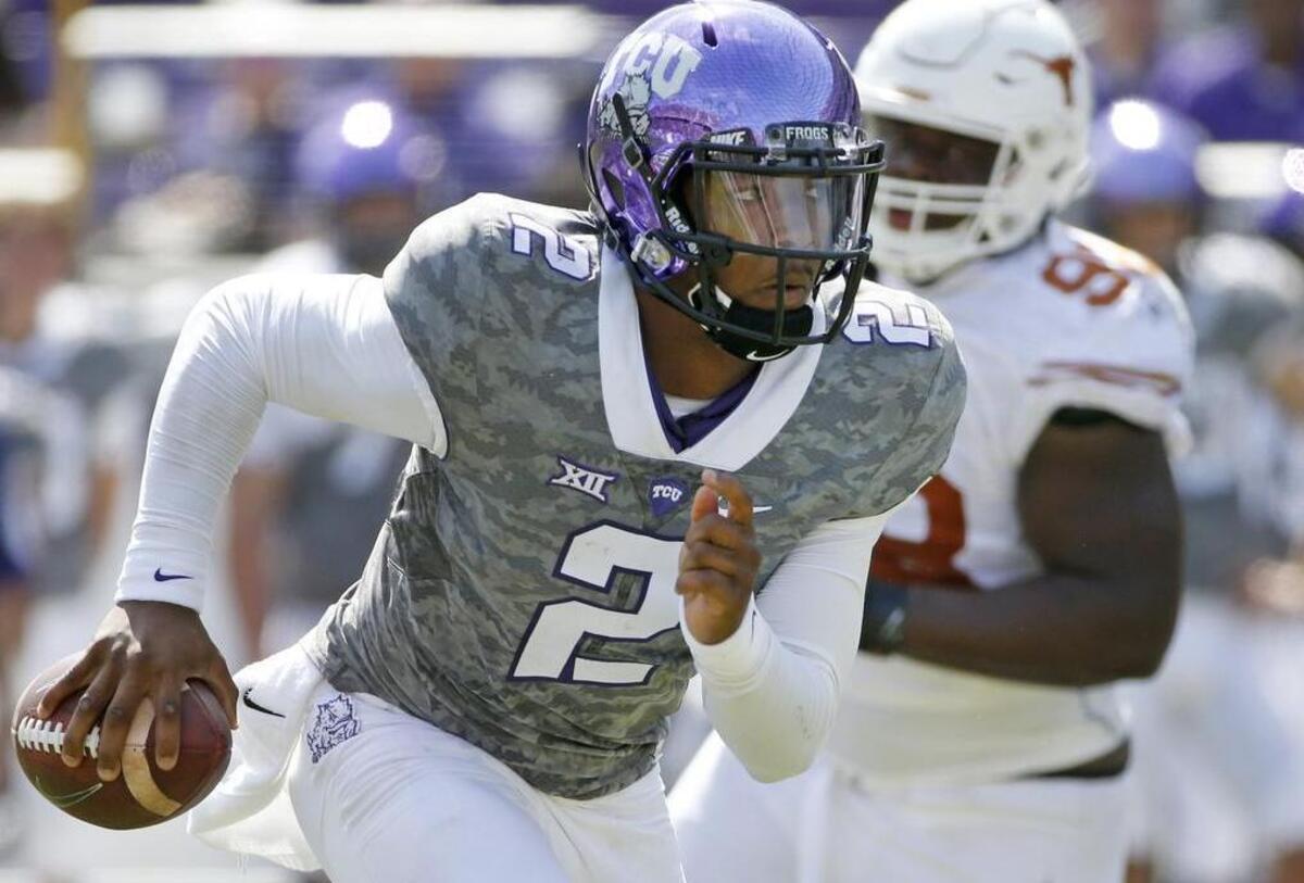 
TCU quarterback Trevone Boykin looks upfield as he gets away from pursuit by Texas’ Hassan Ridgeway. Boykin threw five touchdown passes, setting a school career record, and moved into a share of the national lead this season with 19.
