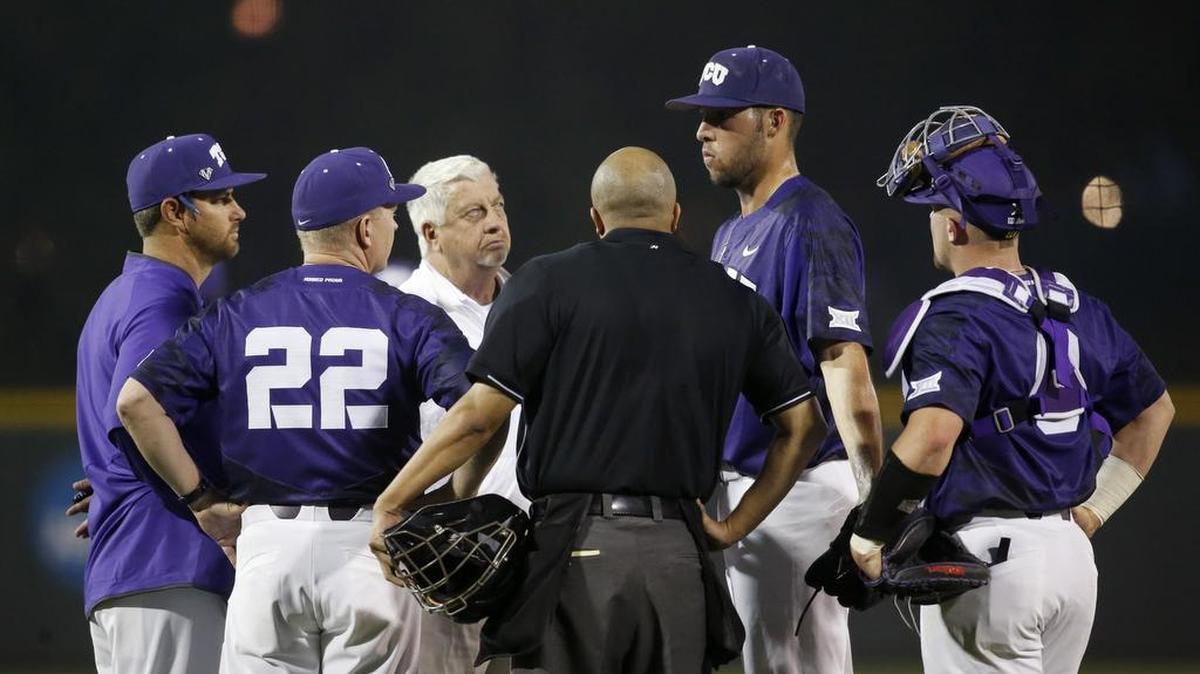 TCU pitcher Mitchell Traver talks with the coaches and trainer on the mound after stopping play in the first inning Tuesday night against Rice. He came out of the game after three batters.