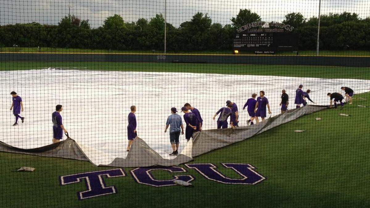 
TCU players pull up the infield tarp after a thunderstorm forced Friday’s game to be postponed.
