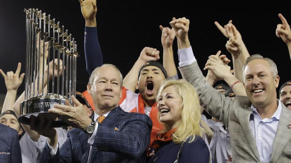 Astros owner Jim Crane holds the championship trophy after Game 7 of the World Series on Wedneday night as his wife and team president Reid Ryan, right, help celebrate.