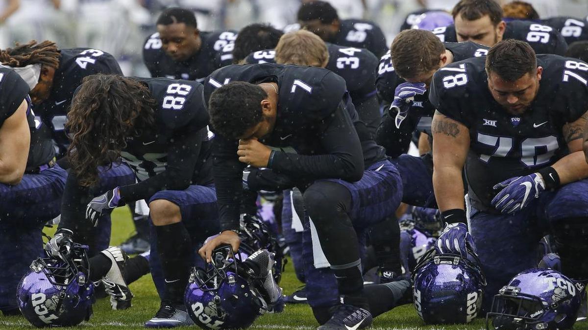 TCU quarterback Kenny Hill (center) kneels with teammates in prayer before the start of Saturday’s game against Kansas State.